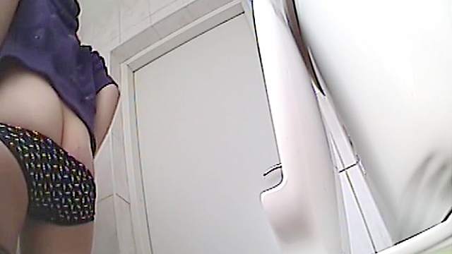 Sweet brunette is peeing in the toilet