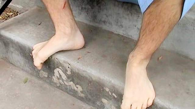 Dark-haired gay rubs his feet outdoors