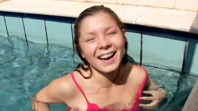 Smiling babe is getting topless in the pool