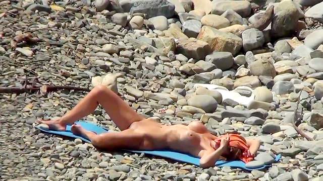 Babe with saggy tits is lying naked on the beach