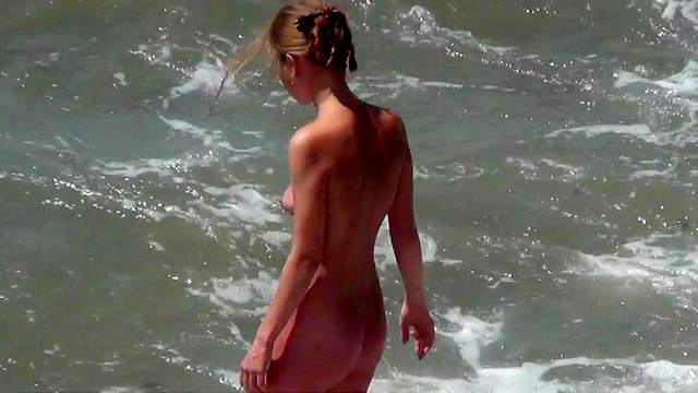 Skinny brunette is walking on the nudist beach
