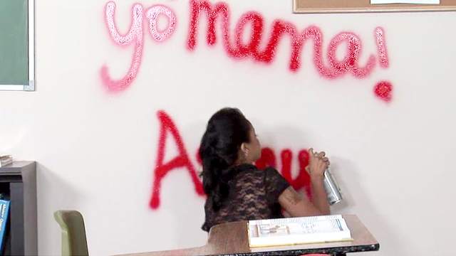 Schoolgirl spray paints the classroom