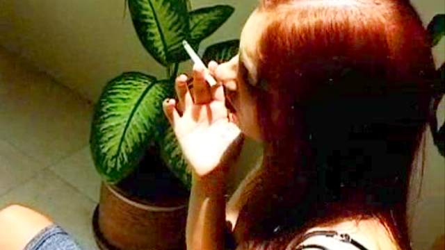 Smoking redhead bares her big tits