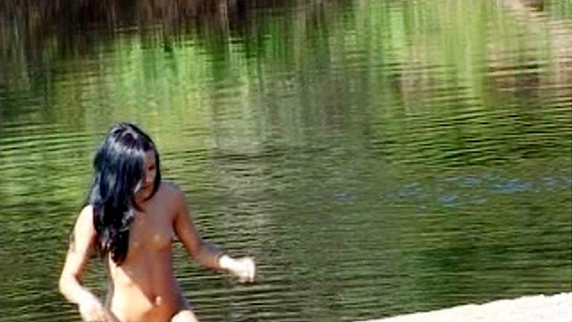 Skinny chick pissing by the lake