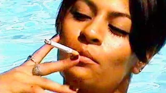 Slender Latina smoking in a sexy way at the poolside