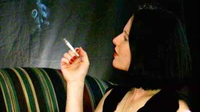 Slender brunette is smoking a cigarette in a hot way