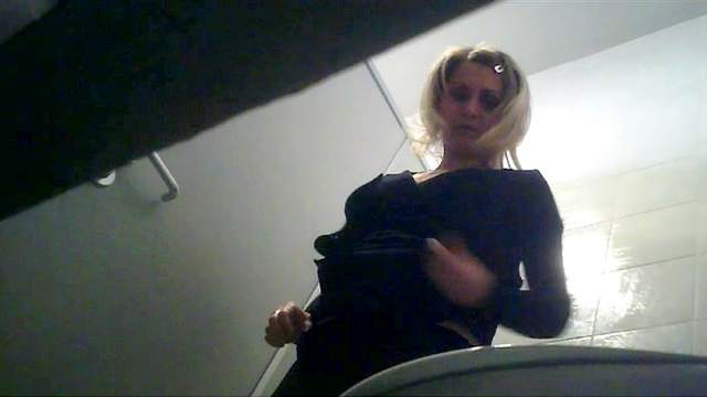 Seductive blonde is pissing in the toilet