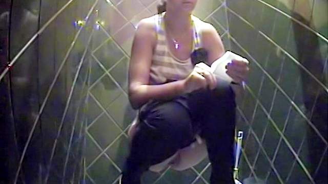 Hot brunette is pissing in the public toilet