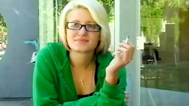 Sexy blonde is smoking a cigarette outdoors