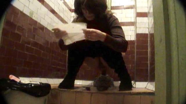 Stunning brunette is reading during peeing